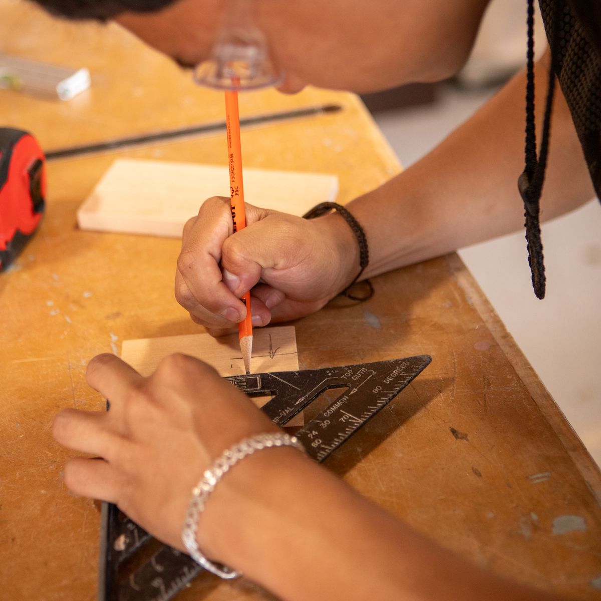 Menuisier traçant des repères au crayon et à l'équerre sur du bois pour des mesures précises
