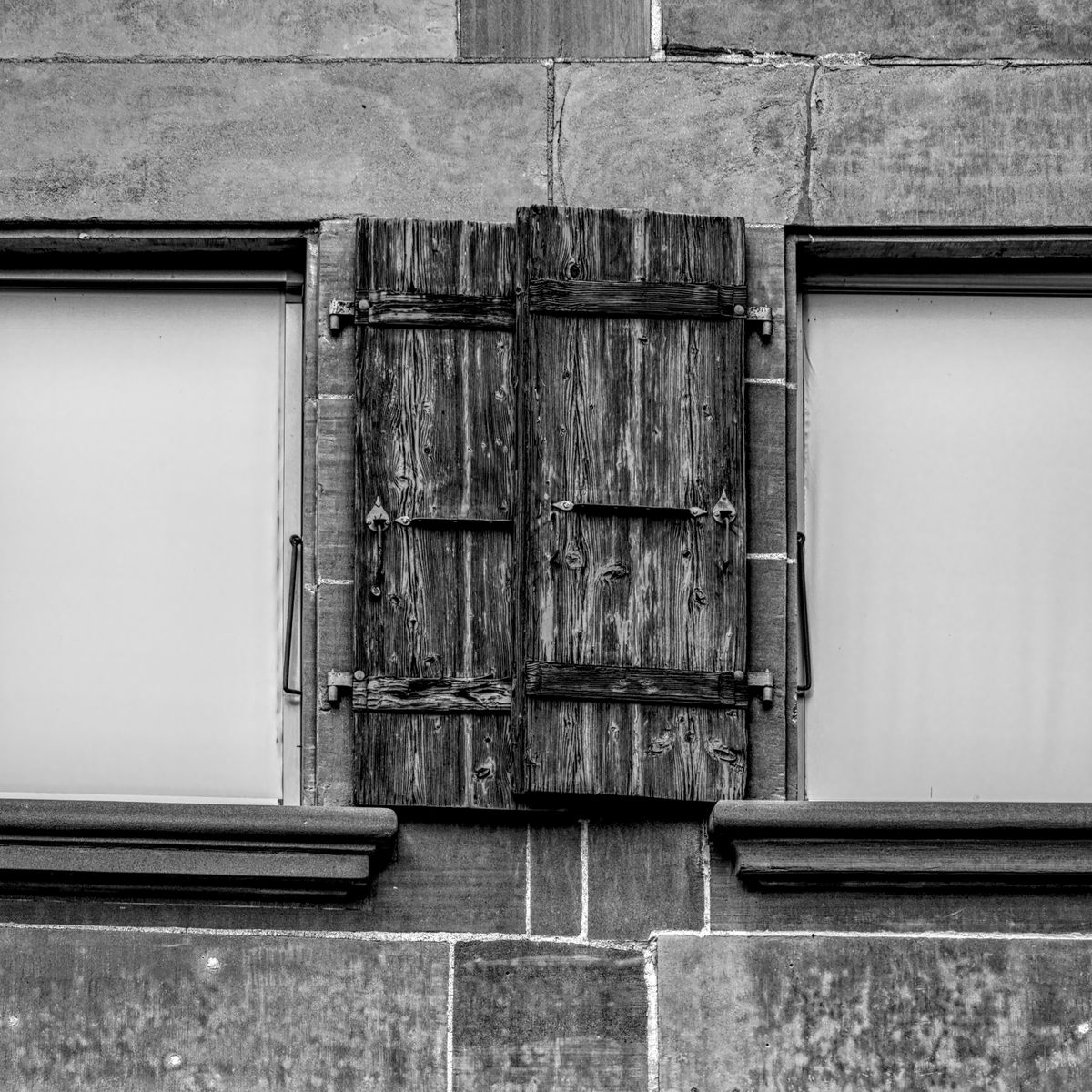 Volets battants en bois rustiques sur la façade en pierre d'un bâtiment ancien