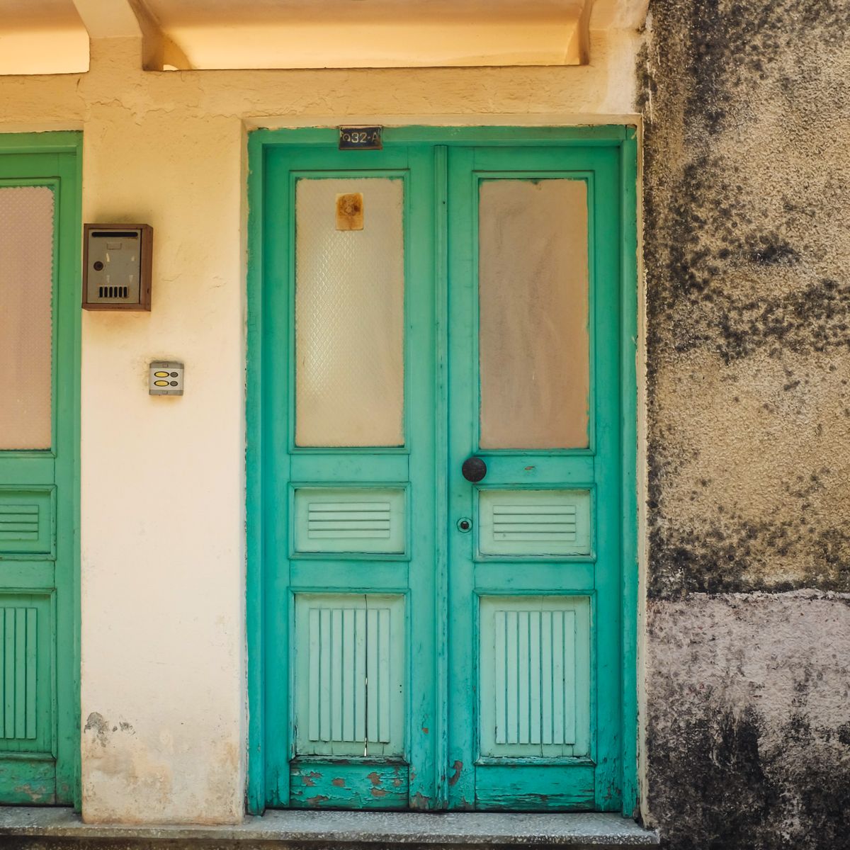 Porte bleu sarcelle vintage sur mur texturé illustrant un choix de matériau et finition